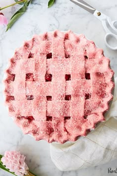 a strawberry pie with powdered sugar on top and pink flowers in the back ground