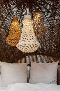 three lamps hanging from the ceiling above a bed