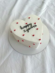 a white heart shaped cake with red hearts on it's side that says happy valentine's day