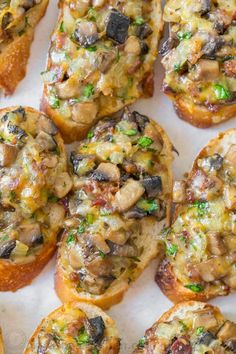 an assortment of small pastries with mushrooms on top and green garnishes