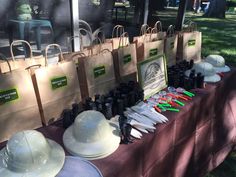 many hats and other items are on the table at an outdoor event with people in the background