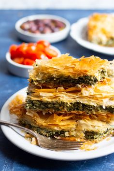 a stack of spinach lasagna on a white plate with a fork next to it