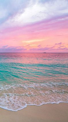 an ocean beach with waves coming in to shore and the sun setting over the water