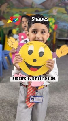 a young boy is holding up a smiley face mask with the caption shapes it's circle, it has no side