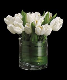 white tulips in a glass vase on a black background