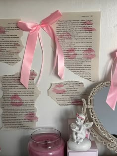 a pink candle and mirror are sitting on a shelf next to a wall with torn up paper