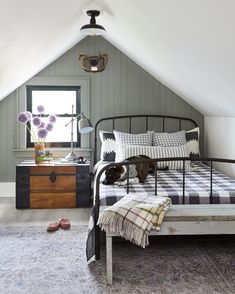 an attic bedroom with a bed, dresser and chest of drawers on the side wall