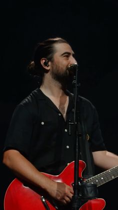 a man holding a red guitar and singing into a microphone