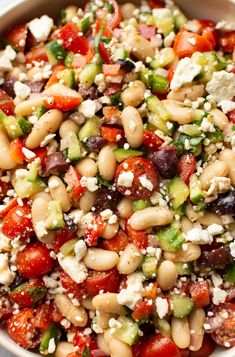 a salad with beans, tomatoes, cucumbers and feta cheese in a bowl