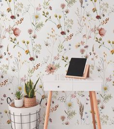 a desk with a laptop on it next to a flower wallpaper