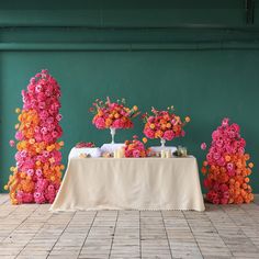 an arrangement of flowers and candles on a table in front of a green wall at a wedding reception