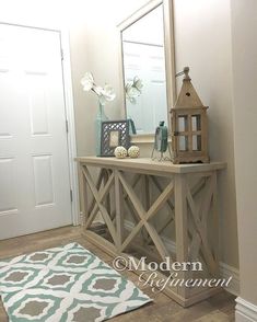 a hallway with a mirror, lamp and rug on the floor in front of it