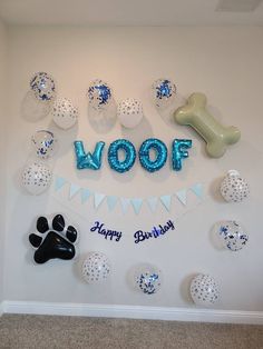 a dog themed birthday party with balloons and decorations on the wall, including a woof balloon