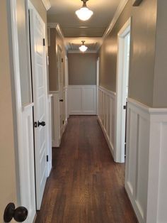 an empty hallway with wood floors and white trim on the walls is seen in this image