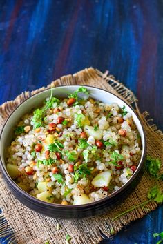 a bowl filled with rice and vegetables sitting on top of a blue cloth next to a spoon