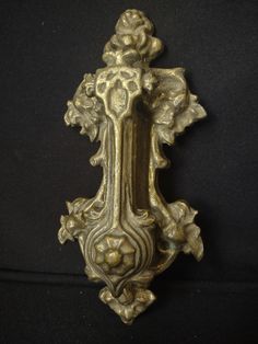 an ornate gold door handle with flowers on it's side and a black background