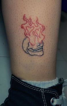 a tattoo on the leg of a person with a skull and flames coming out of it