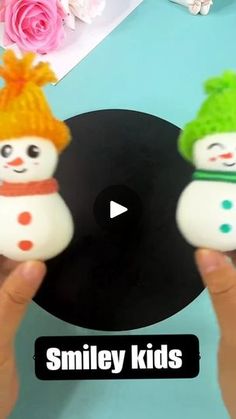 someone is holding two small snowmen in their hands