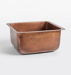 a square copper colored metal container on a white background