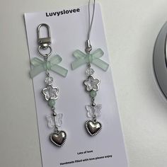 a pair of earrings with charms attached to them sitting next to a clock on a table