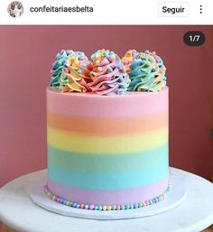 a multicolored cake with sprinkles and rainbow frosting on top