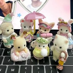 a group of small toy animals sitting on top of a laptop computer keyboard with an image of a woman in the background