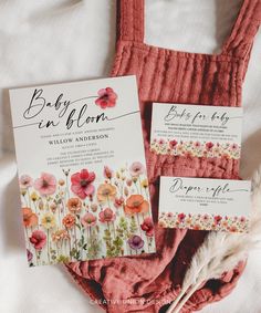 the wedding stationery is laid out on top of an unmade bed with flowers and feathers