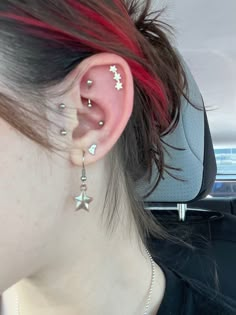 a woman with red hair and piercings on her ear in the back seat of a car