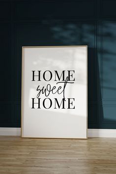 a white framed poster sitting on top of a hard wood floor next to a blue wall