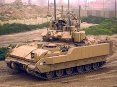 an army tank driving down a dirt road