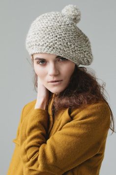 a young woman wearing a knitted hat with pom - poms on it