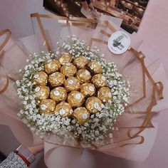 a bouquet of baby's breath and chocolates wrapped in gold foil on a table