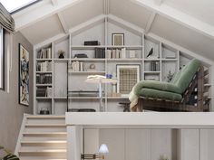 a living room filled with furniture and bookshelves next to a stair leading up to a loft