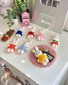 small crocheted animals are sitting on top of a white table next to a potted plant