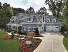 a large blue house with lots of trees and shrubs around it's front entrance