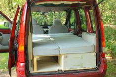 the back end of a red van with mattresses in it