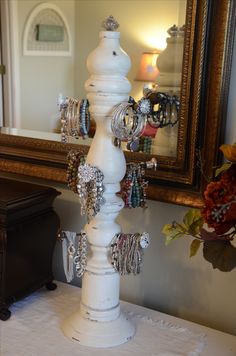 a white jewelry holder on top of a table with a mirror in the back ground