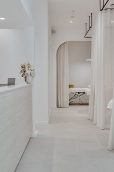 a room with white walls and flooring has curtains on the wall, along with a desk