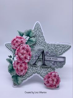 a star shaped card with pink flowers and the letter a on it's side