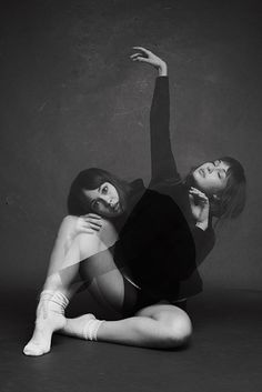 two women are sitting on the floor posing for a black and white photo with their arms in the air