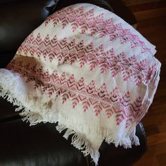 a white and pink blanket sitting on top of a black chair