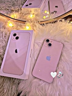 two pink iphone cases sitting next to each other on a furry surface with lights in the background