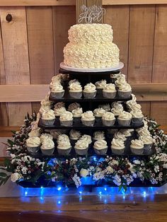 a triple tiered cake with cupcakes on it