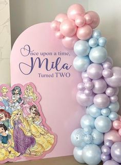 there is a balloon arch that says once upon a time, mia turned two on it