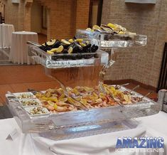 two trays filled with different types of food on top of a white table cloth