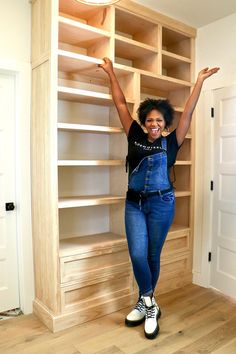 a woman standing in front of a bookcase with her hands up and arms outstretched