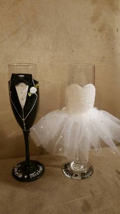 two wine glasses with tuxedo and bride's dress on them sitting next to each other