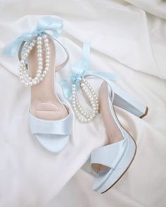 "An all time classic and elegance with simplicity of satin block heels sandal adorned with double pearls ankle strap for a sweet and romantic look. Perfect for brides, bridesmaids, prom night, date night, and definitely a highlight on every special occasions. The delicate pearl beads are placed carefully by hand made to order to create a graceful classic bridal shoe. DETAILS: HEELS: 4 inches COLORS AVAILABLE: Ivory, White, and Light Blue UPPER: Synthetic upper and lining MATERIALS: Manmade outsole ORIGIN: Imported STYLE NAME: ATHENA  Not sure of which size to purchase? Shoes measurements are as follow: (Please note measurements taken the length of inside of shoe from toe to heel) SIZE 5 - 9\" SIZE 6 - 9.25\" SIZE 7 - 9.5\" SIZE 8 - 10.875\" SIZE 9 - 10.25\" SIZE 10 - 10.50\"  SIZE 11 - 10. Bridal Wedding Shoes Heels, Prom Shoes Short Heel, White And Blue Heels, Heels Light Blue, Light Blue Prom Shoes, Bride Platform Heels, Blue Shoes For Wedding, Light Blue Prom Heels, Light Blue Heels Wedding