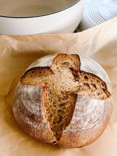 a loaf of bread sitting on top of a piece of paper next to a bowl