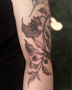 a woman's arm with flowers and leaves tattooed on the left side of her arm